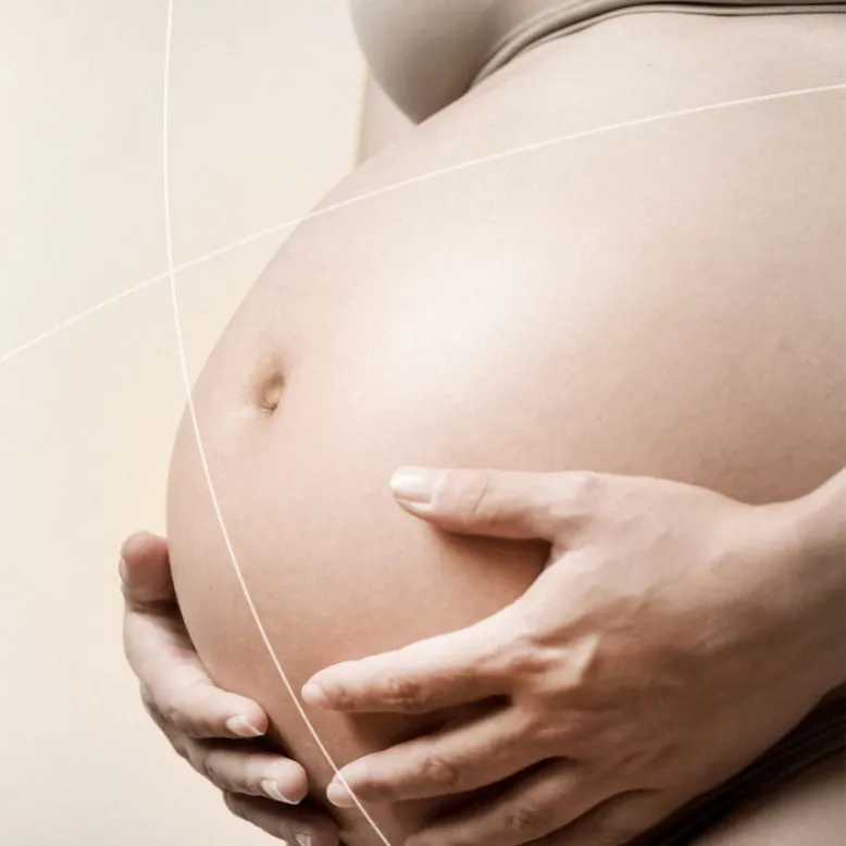 Mujer en embarazo tocando su barriga.